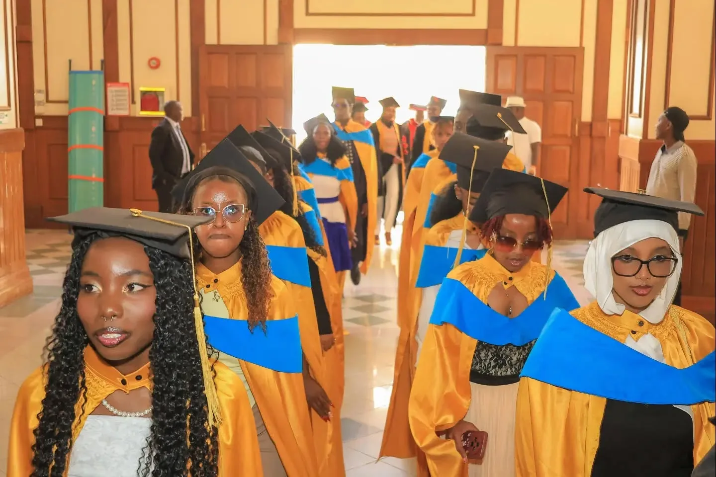 KENCID graduates in academic gowns processing through a graduation hall