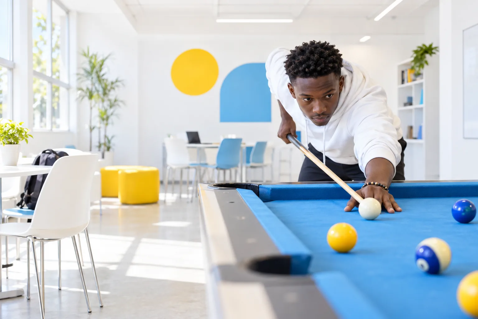 Student playing billiards in a bright college activity room